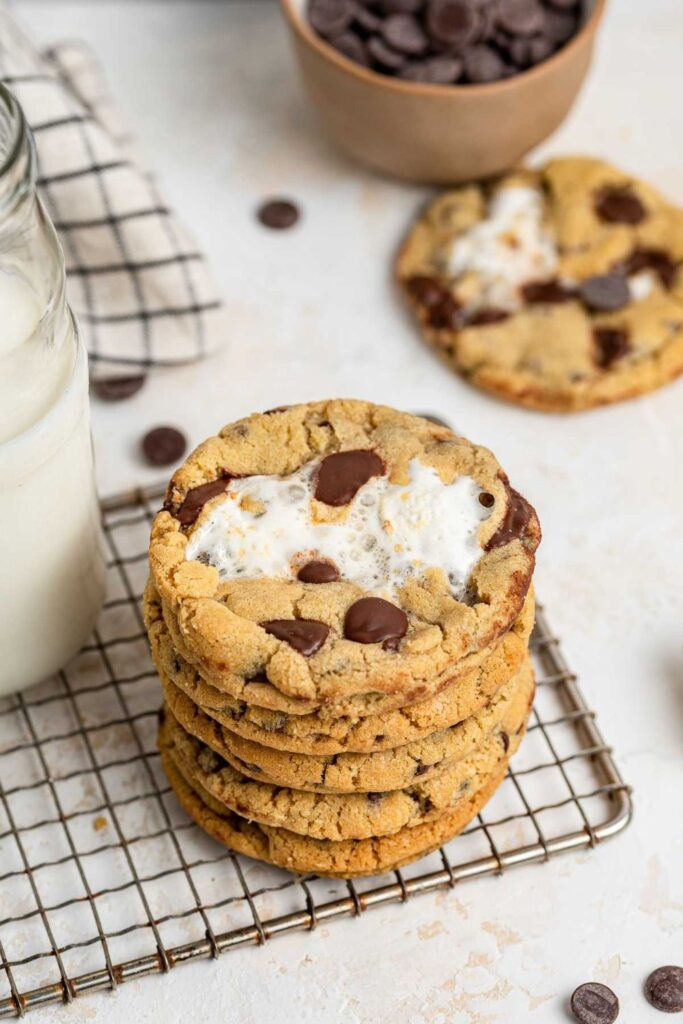 stack of chocolate chip marshmallow cookies on rack with milk