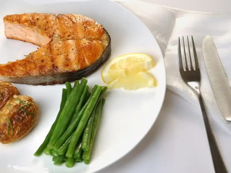 Rosemary salmon and veggies in plate with fork