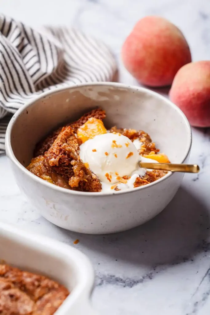 warm serving of peach cobbler in a white bowl