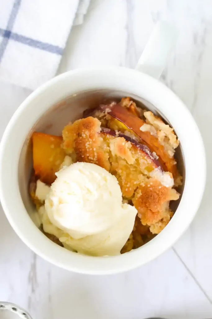 A golden-brown peach cobbler in a baking dish, with juicy peach slices peeking through the buttery, crispy topping