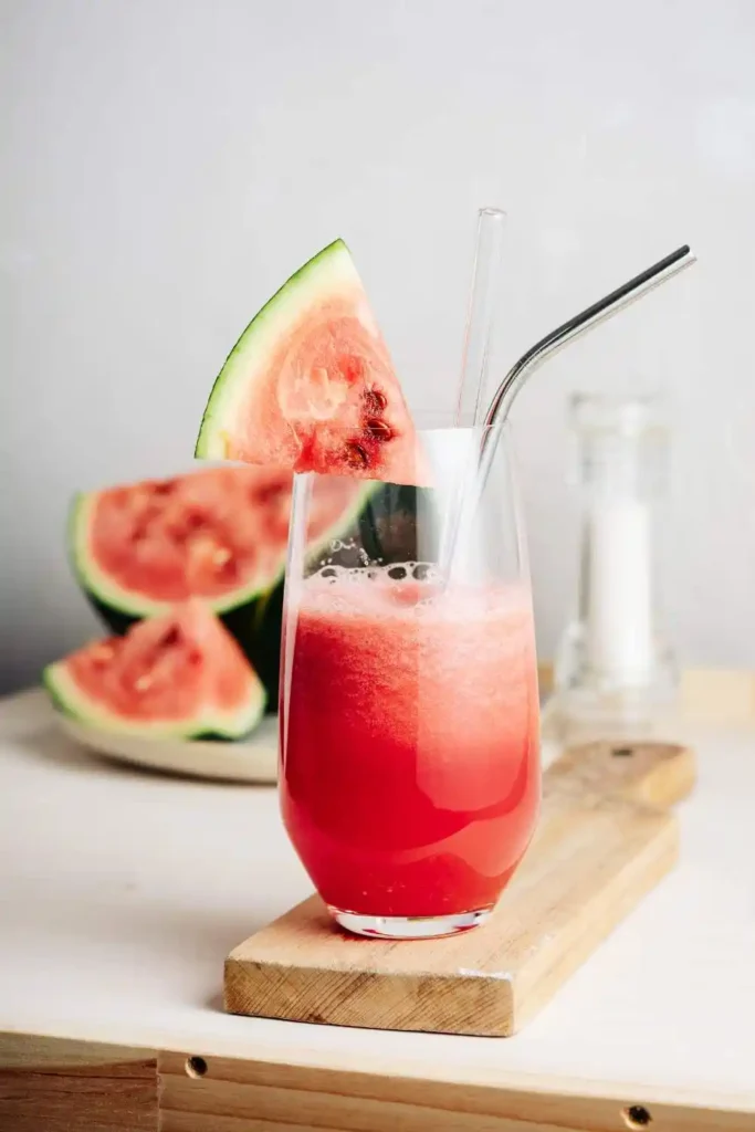 glass of Watermelon Agua Fresca with a drinking straw, garnished with fresh mint leaves.