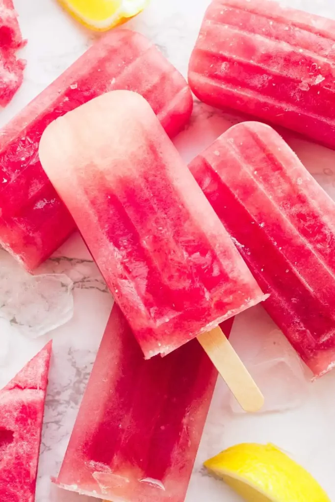 The bright pink popsicles are complemented by fresh mint leaves and small watermelon wedges