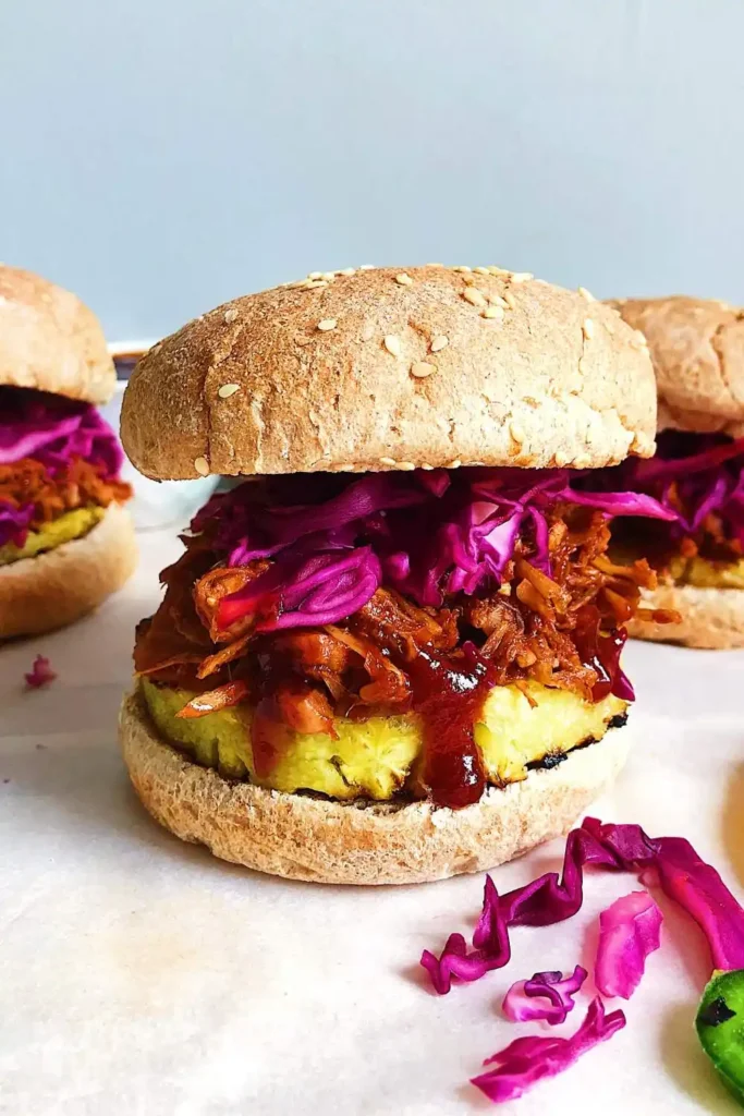 sandwich filled with shredded BBQ jackfruit, topped with grilled pineapple slices and a vibrant cabbage slaw