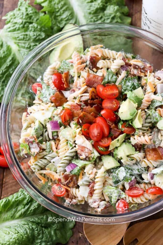 A white bowl filled with BLT Pasta Salad, showcasing colorful layers of pasta, crispy bacon, fresh lettuce, juicy tomatoes