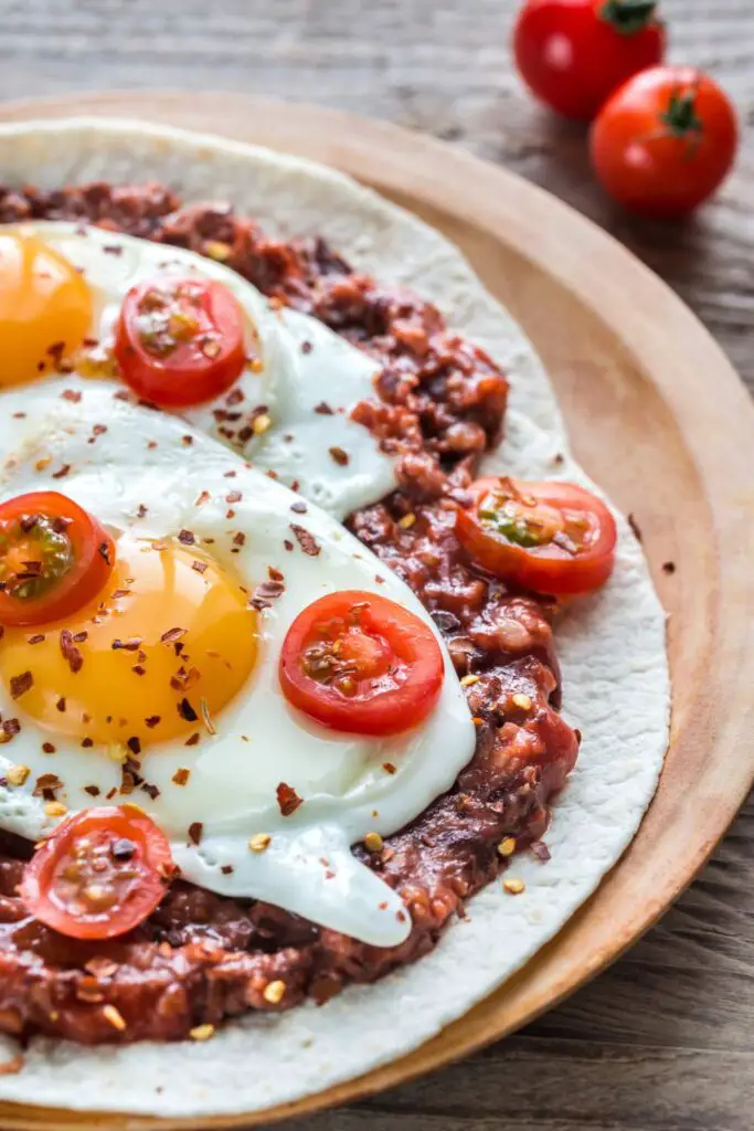 baked huevos rancheros on a white plate, featuring a perfectly cooked egg with a runny yolk nestled in a bed of spiced tomato sauce