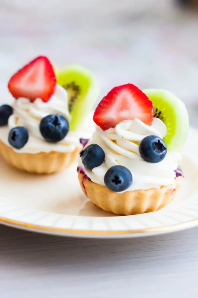 Colorful fruit tarts topped with an assortment of fresh berries, kiwi, and mango slices