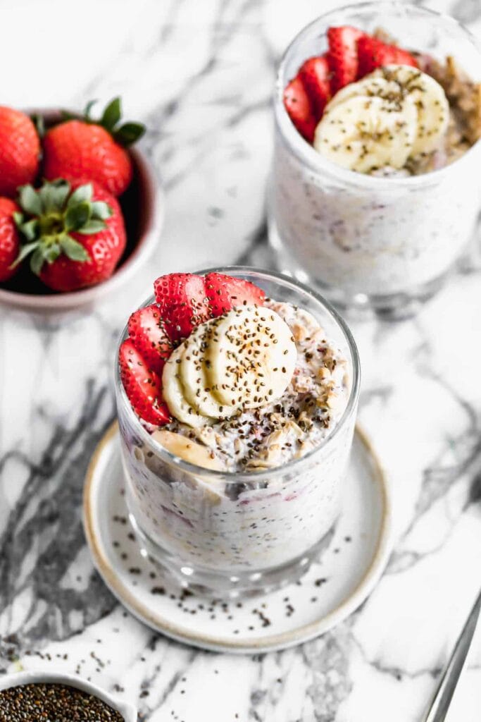 A jar of overnight oats filled with fresh strawberries, yogurt, and oats, garnished with sliced strawberries on top