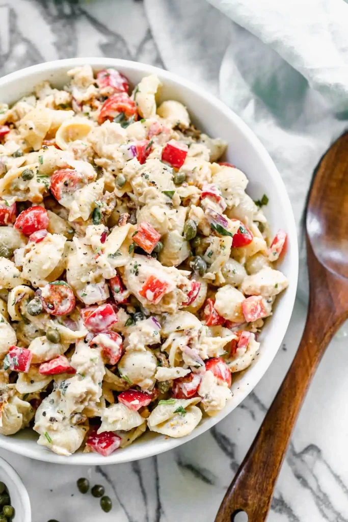 Tuna Pasta Salad featuring spiral pasta, chunks of tuna, diced celery, cherry tomatoes, and red onion, all mixed in a creamy dressing