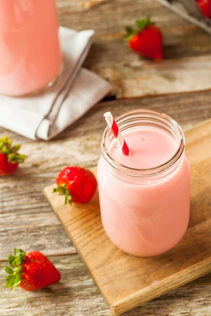 one glass of strawberry milk on wooden table 