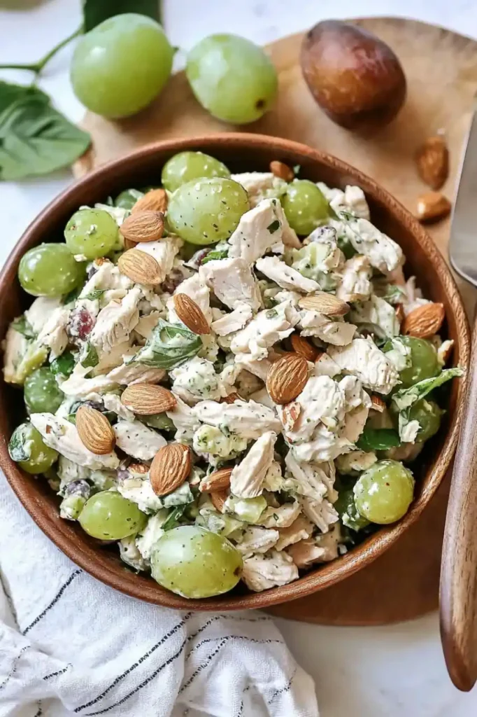 Chicken Salad with Grapes and Almonds in wooden bowl on wooden noard and is nearly grapes are scattered