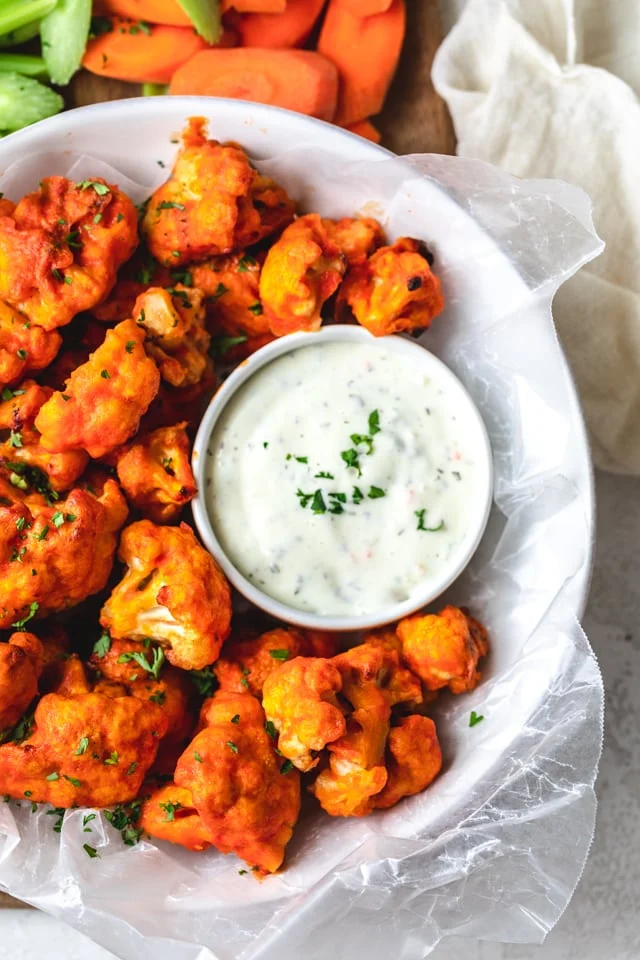 Baked Buffalo Cauliflower Bites with sauce in white plate