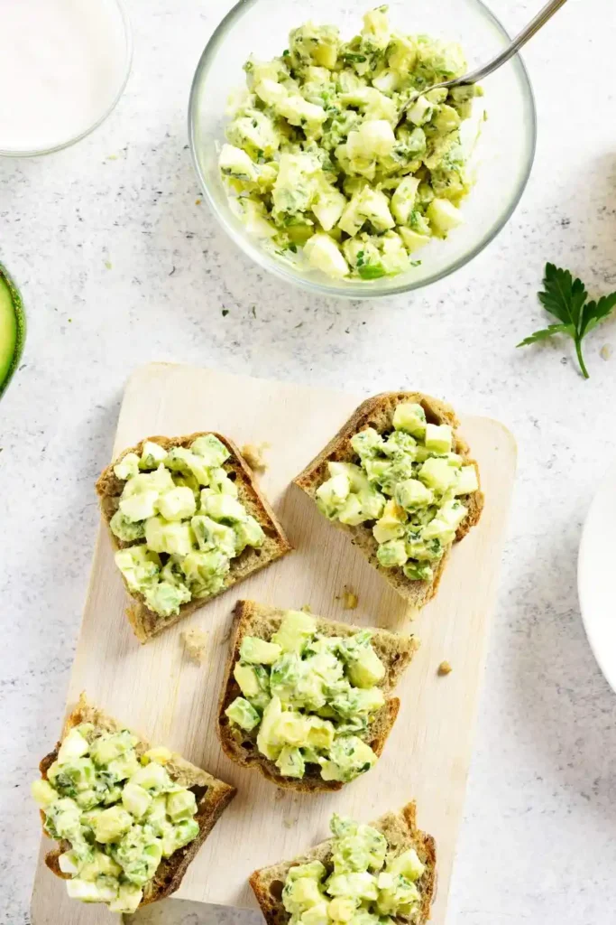 Avocado Egg Salad With Greek Yogurt on crackers arranged on wooding table