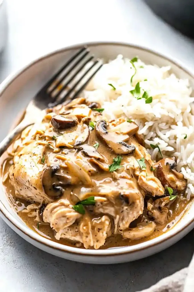 close view of 3-Ingredient Creamy Mushroom Crockpot Chicken in bowl with fork place in it