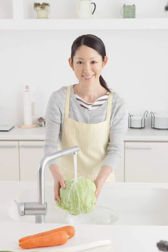 woman washing cabbage in kitchen