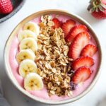 strawberry banana smoothie bowl with strawberry, banana and granola topping
