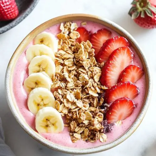 strawberry banana smoothie bowl with strawberry, banana and granola topping