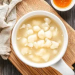 fish maw soup in white bowl placed on wooden table