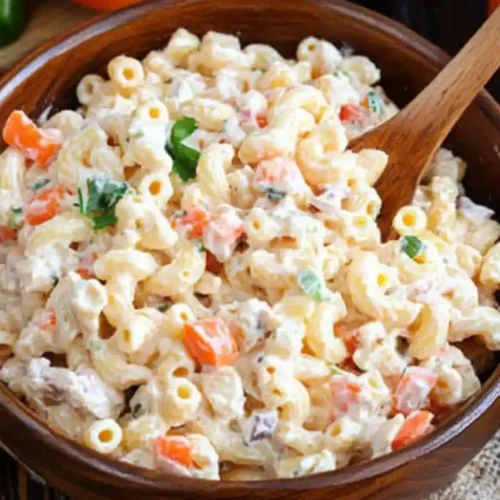 Chicken Macaroni Salad With Nestle Cream in wooden bowl and two tomatoes are placed nearby