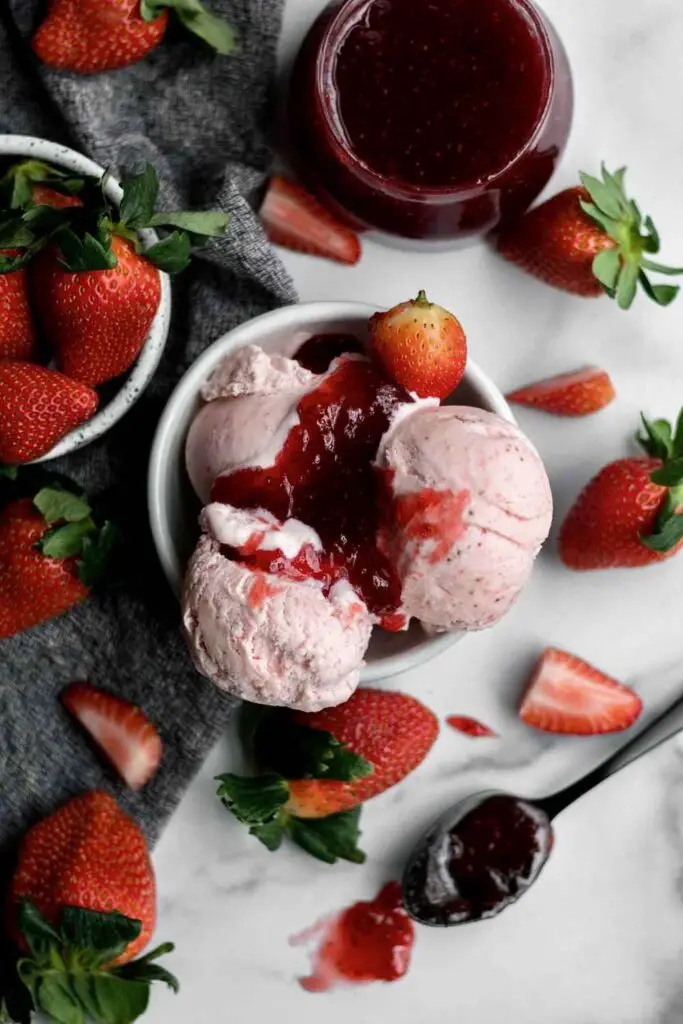 Gluten free srawberry ice cream in bowl with strawberring toppings
