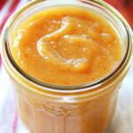 peach butter in glass jar and peach and napkin is partially visible in background