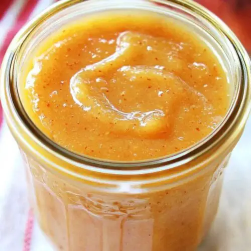 peach butter in glass jar and peach and napkin is partially visible in background
