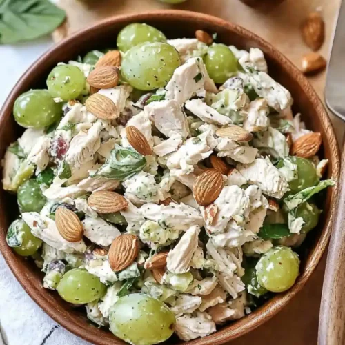 Chicken Salad with Grapes and Almonds in wooden bowl on wooden noard and is nearly grapes are scattered