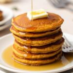 stacks of oatmeal pancakes drizzle with maple syrup