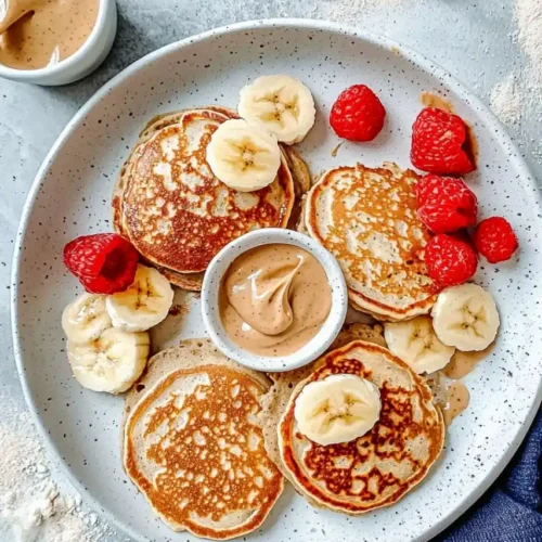 top down view of pancakes in white plate and strawberries scatter around