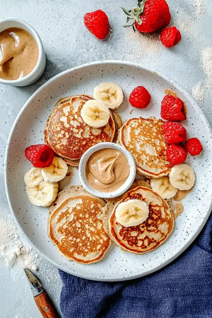 top down view of pancakes in white plate and strawberries scatter around